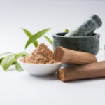 Sandalwood powder with traditional mortar, sandalwood sticks, perfume or oil and green leaves
