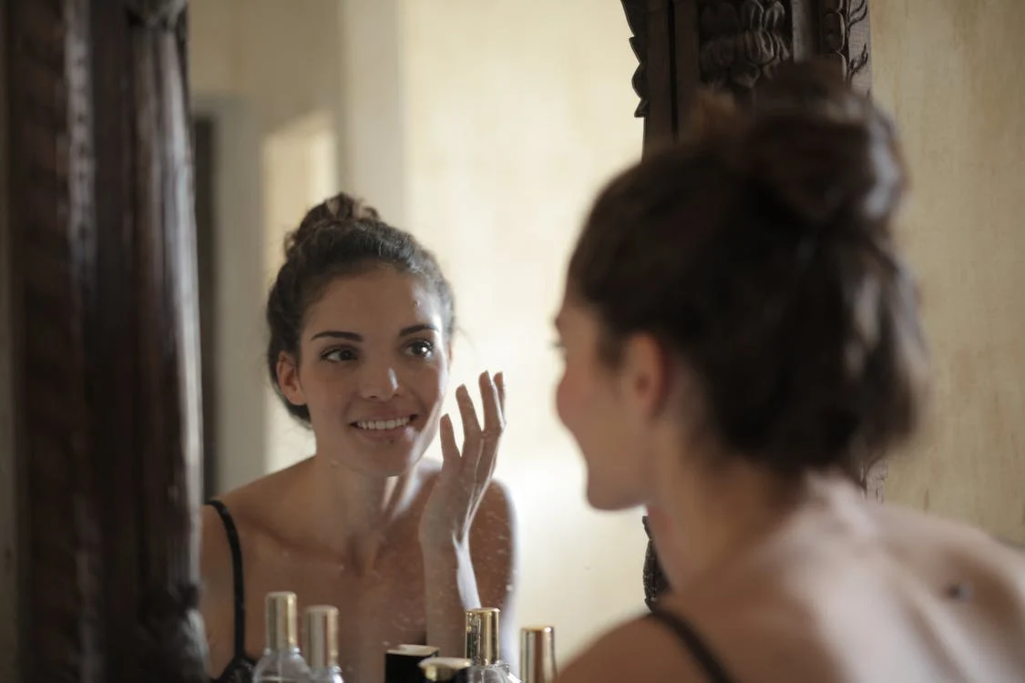 A woman applying skincare looking at the mirror