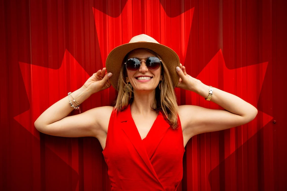 woman in a red sleeveless dress with a Canada flag printed background