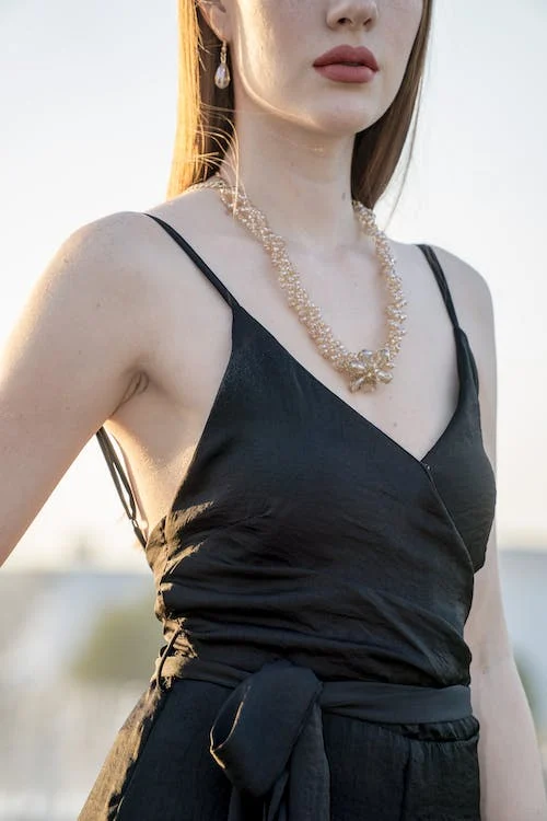 woman wearing black spaghetti strap dress and gold colored necklace