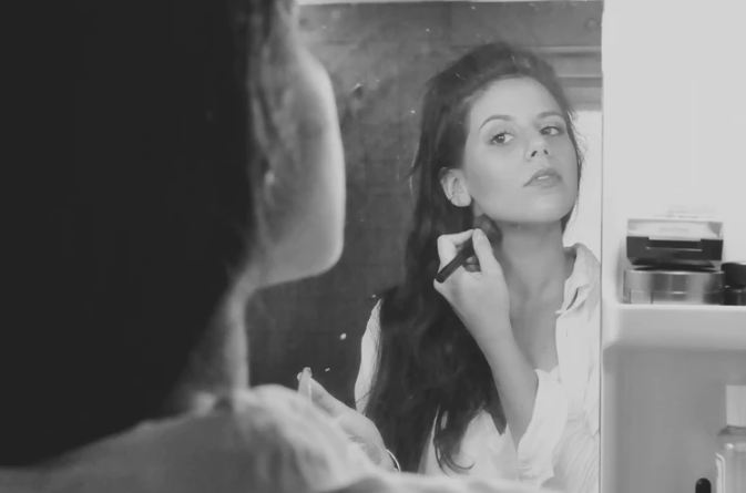 A-black-and-white-photo-of-a-girl-applying-makeup