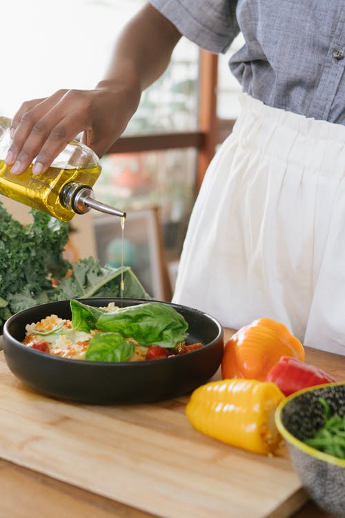 A-person-pouring-olive-oil-on-vegetables-in-a-bowl
