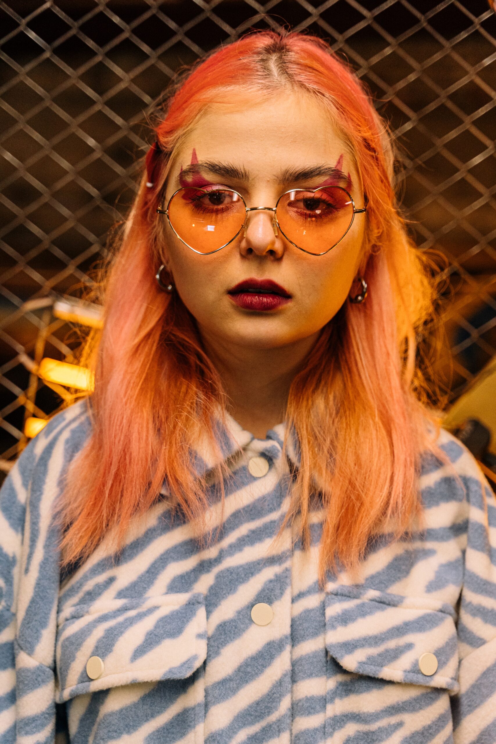 Young woman with pink hair wearing heart-shaped glasses