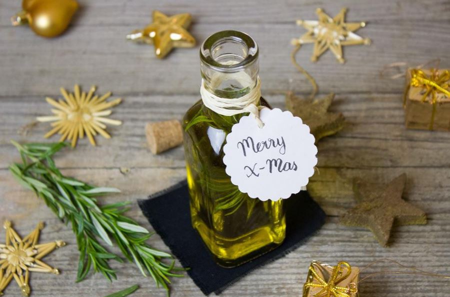 a-bottle-of-rosemary-essential-oil-with-a-Merry-Christmas-tag-surrounded-by-fresh-rosemary-and-christmas-ornaments