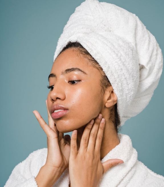 calm-african-american-female-in-bathrobe-touching-face-against-blue-background