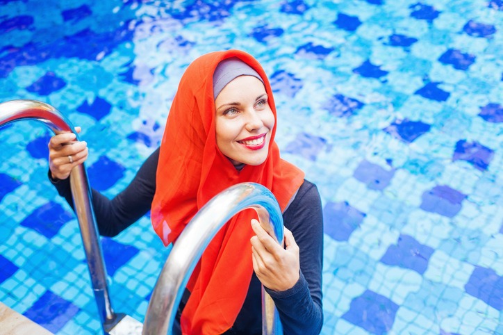 muslim caucasian woman swimming in a swimming pool