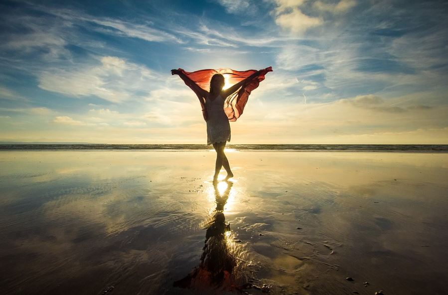 silhouette-of-a-woman-at-the-beach-holding-a-scarf-up-in-the-air