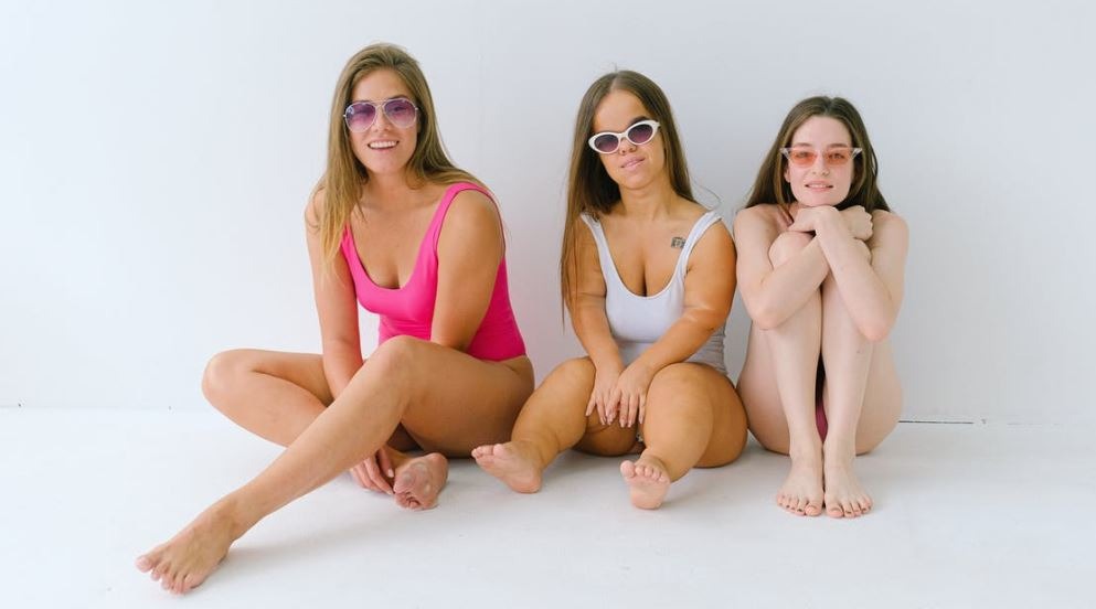 three-women-sitting-on-the-floor-wearing-swimsuits