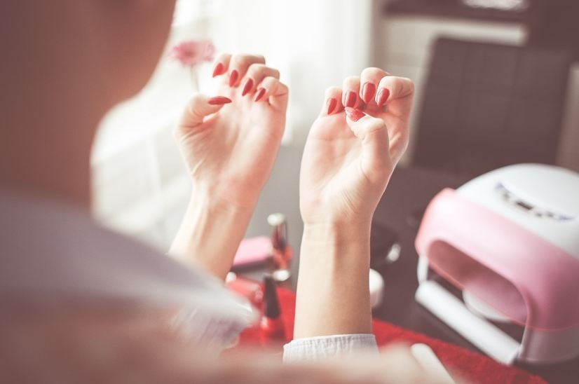 woman-looking-at-her-red-nails-different-nail-polish-on-the-table-white-and-pink-UV-Lamp-for-nails